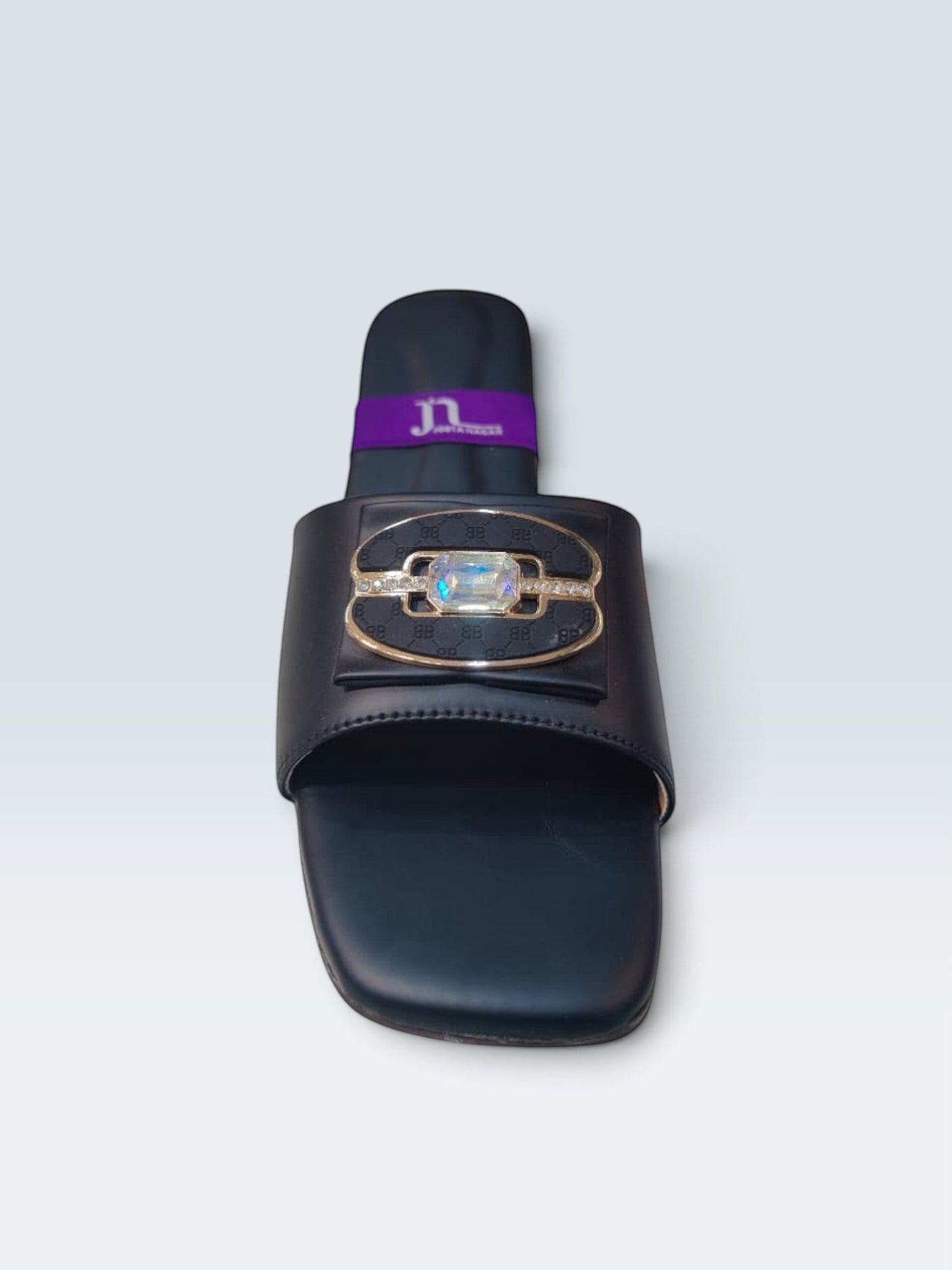 My Store 2 black flat slide sandals featuring a central crystal-inspired stone, gold-tone hardware, and monogram detail