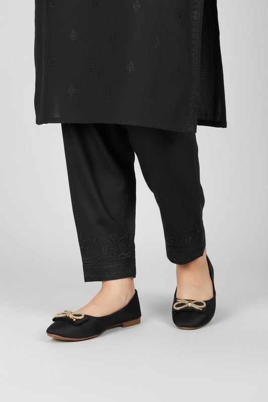 My Store 2 black pointed-toe ballet flats featuring a gold-tone crystal bow, worn with black embroidered trousers.