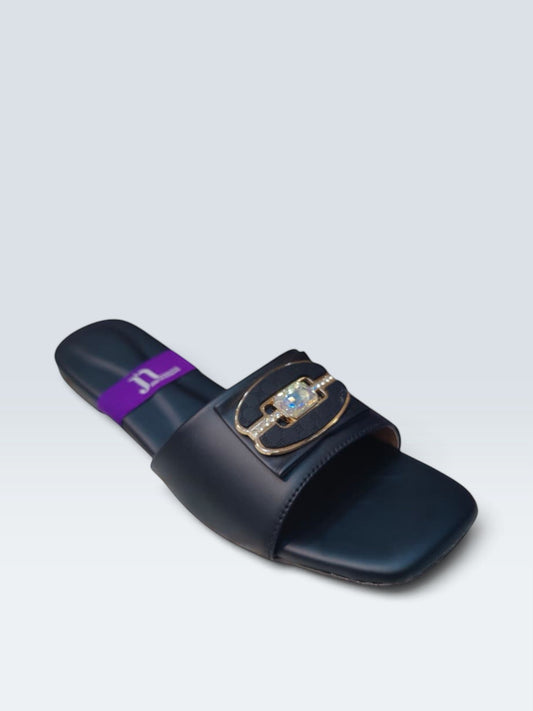 My Store 2 black flat slide sandals featuring a central crystal-inspired stone, gold-tone hardware, and monogram detail.